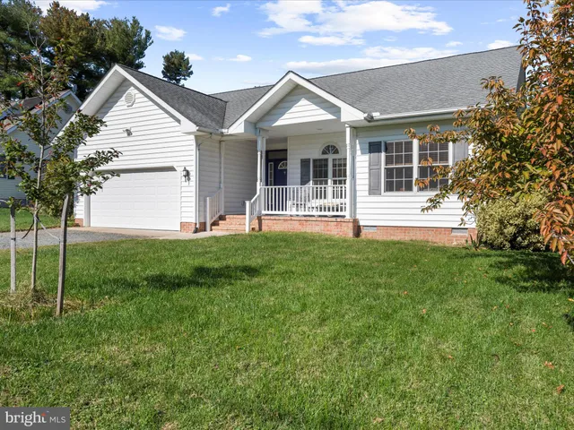 a front view of a house with a yard and large tree