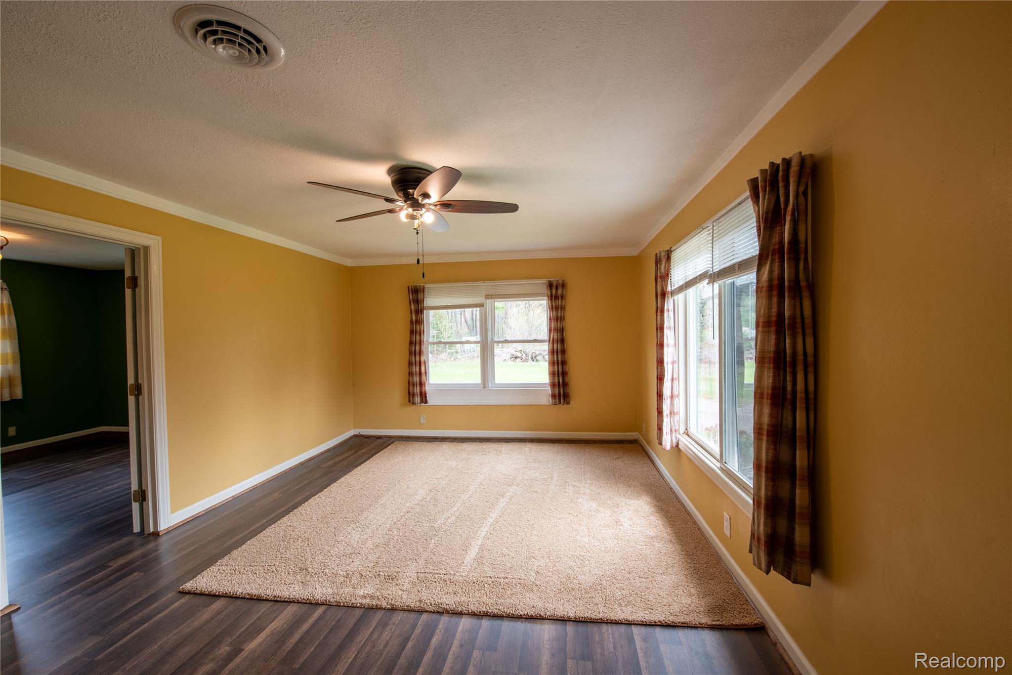 1190 Meadow Road Tawas City, MI 48763 - Photo 9 of 26 Empty room featuring ornamental molding, a ceiling fan, and dark wood-style flooring