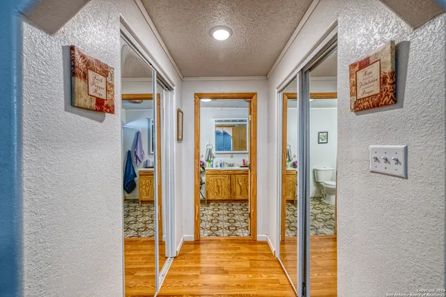 a view of a hallway with wooden floor and a bathroom