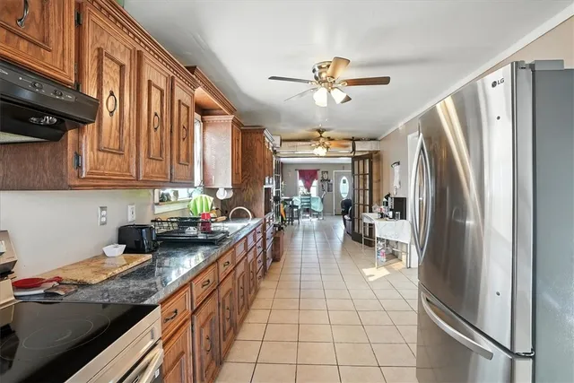 a kitchen with stainless steel appliances granite countertop a refrigerator a sink dishwasher a stove and white cabinets with wooden floor