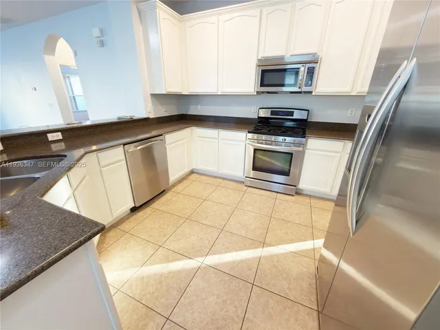 a kitchen with granite countertop a stove a sink and a microwave