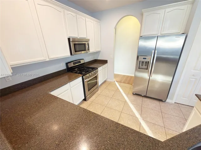 a kitchen with stainless steel appliances granite countertop a refrigerator a stove and a sink
