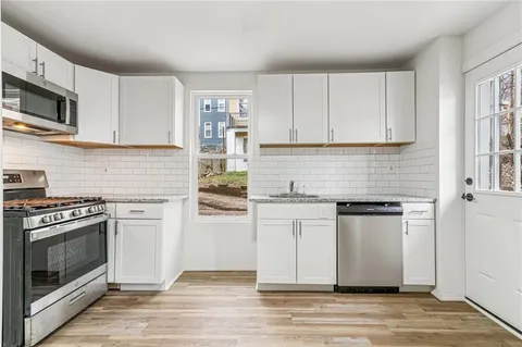 a kitchen with stainless steel appliances granite countertop a stove a sink and white cabinets