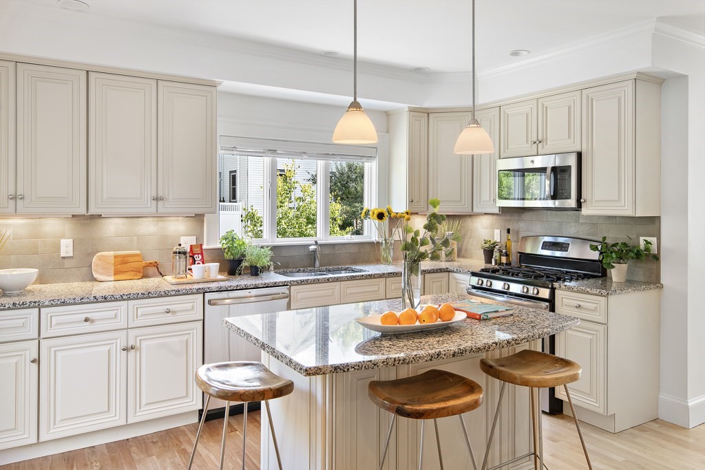 106 Florence Avenue Arlington, MA 02476 - Photo 6 of 32 a kitchen with stainless steel appliances granite countertop a stove a sink a microwave a dining table and chairs with wooden floor