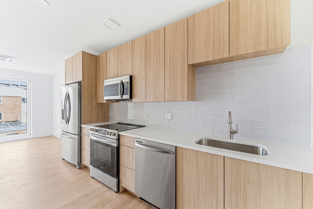 1035 Commonwealth Avenue, Unit 608 Boston, MA 02215 - Photo 2 of 13 a kitchen with stainless steel appliances granite countertop a sink stove and refrigerator