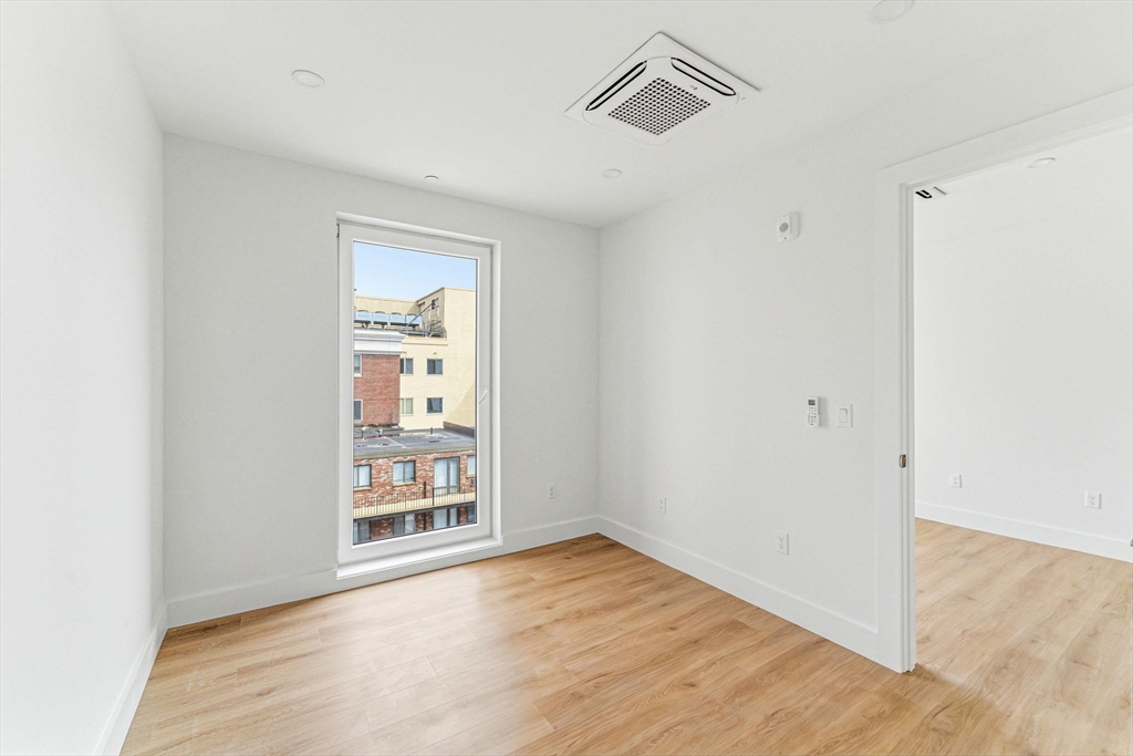1035 Commonwealth Avenue, Unit 608 Boston, MA 02215 - Photo 5 of 13 an empty room with wooden floor cabinet and windows