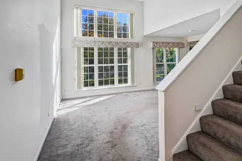 a view of an empty room with wooden floor and a ceiling fan
