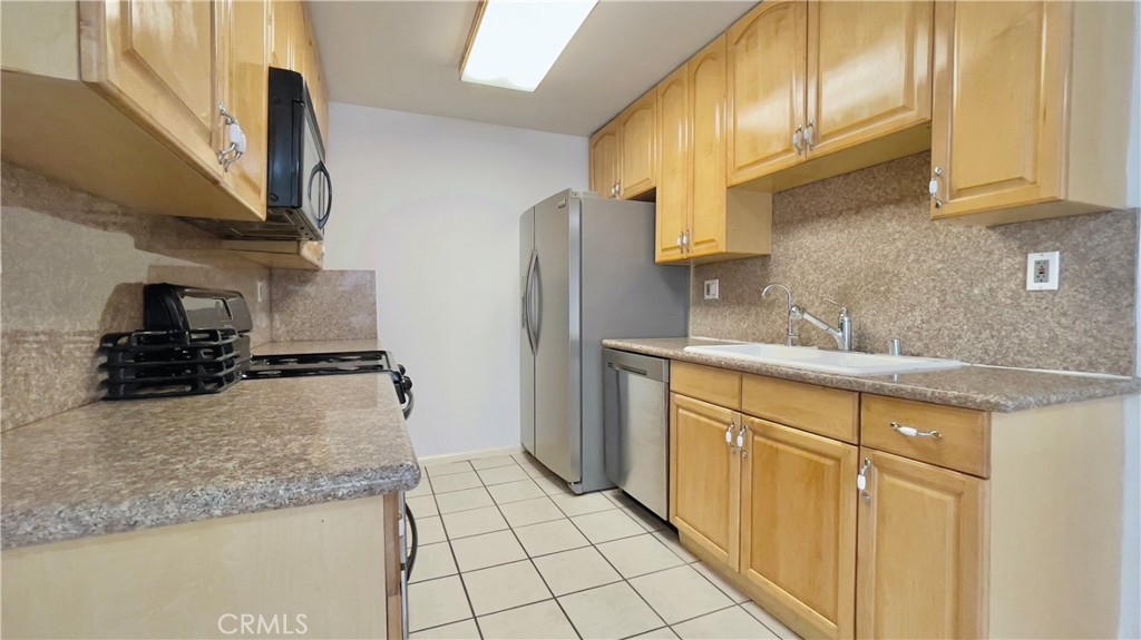 2911 4th Street, Unit 116 Santa Monica, CA 90405 - Photo 5 of 21 a kitchen with stainless steel appliances granite countertop a sink a stove and a refrigerator