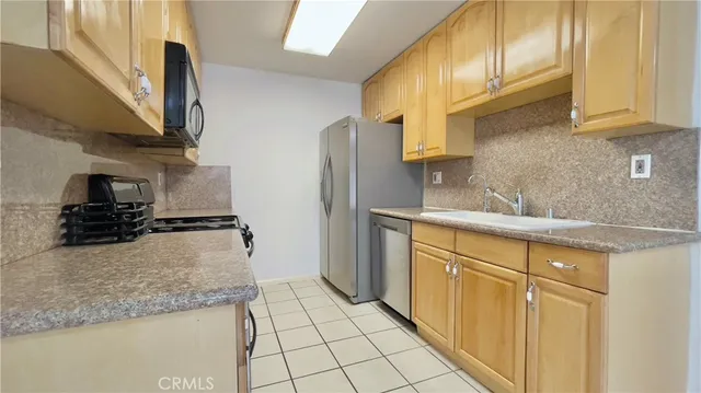 a kitchen with stainless steel appliances granite countertop a sink a stove and a refrigerator