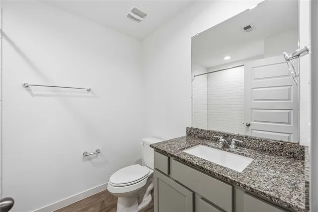 a bathroom with a granite countertop sink a toilet and a mirror