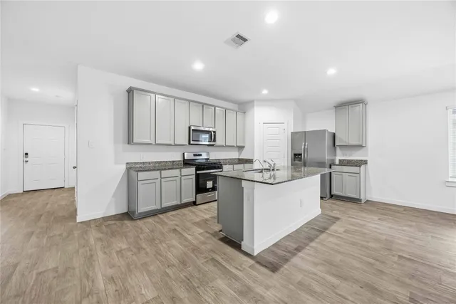 a kitchen with granite countertop white cabinets and stainless steel appliances