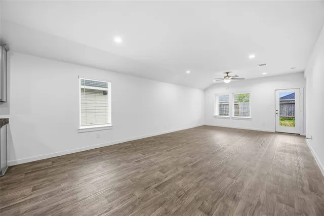 an empty room with wooden floor and windows