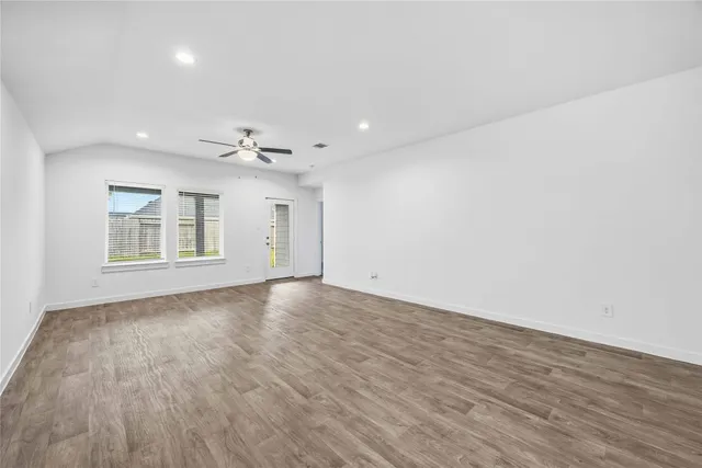 a view of an empty room with wooden floor and a window