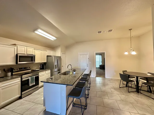 a kitchen with kitchen island granite countertop a sink counter and chairs