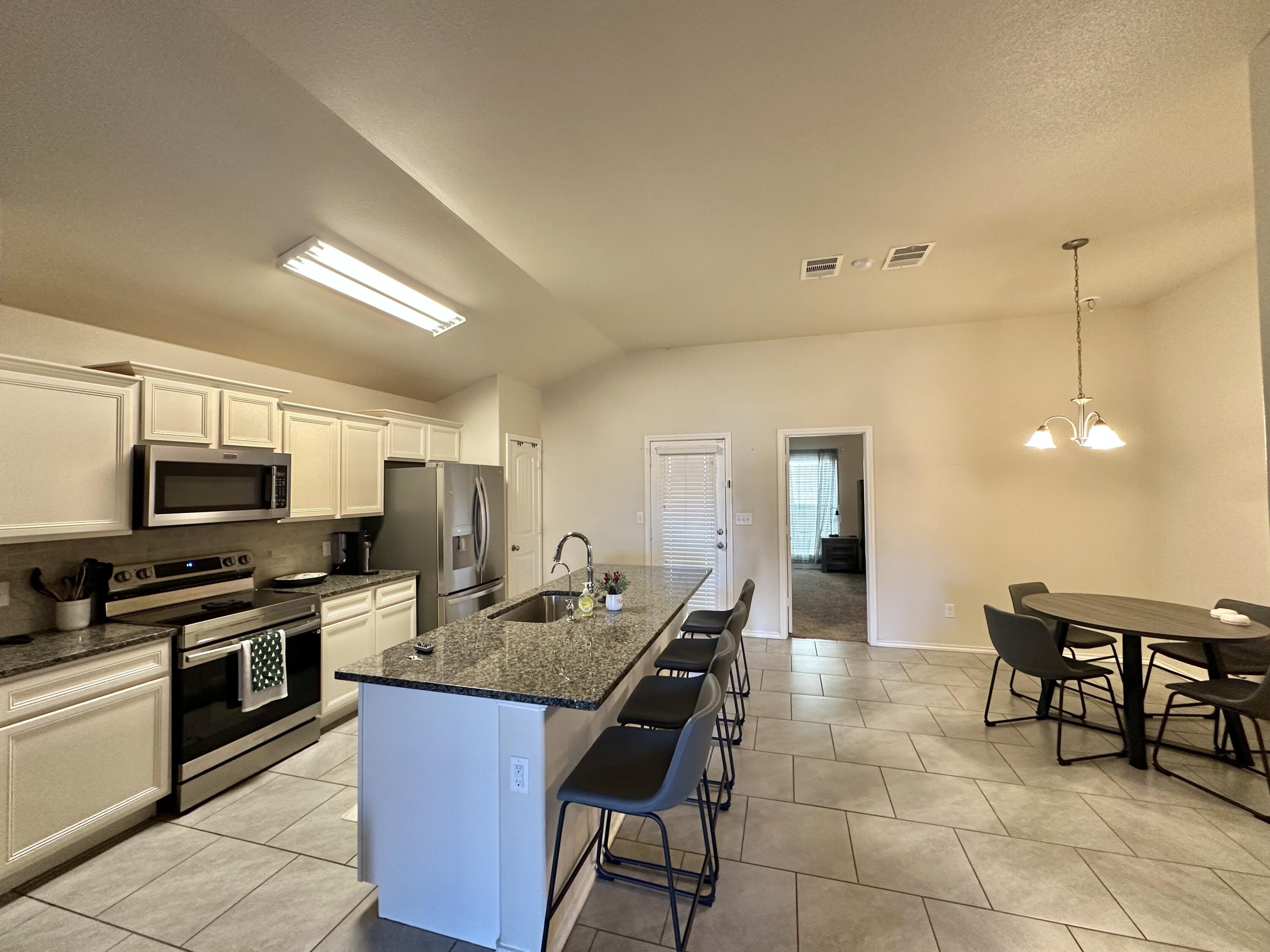 10411 Valencia Avenue Lubbock, TX 79424 - Photo 2 of 16 a kitchen with kitchen island granite countertop a sink counter and chairs
