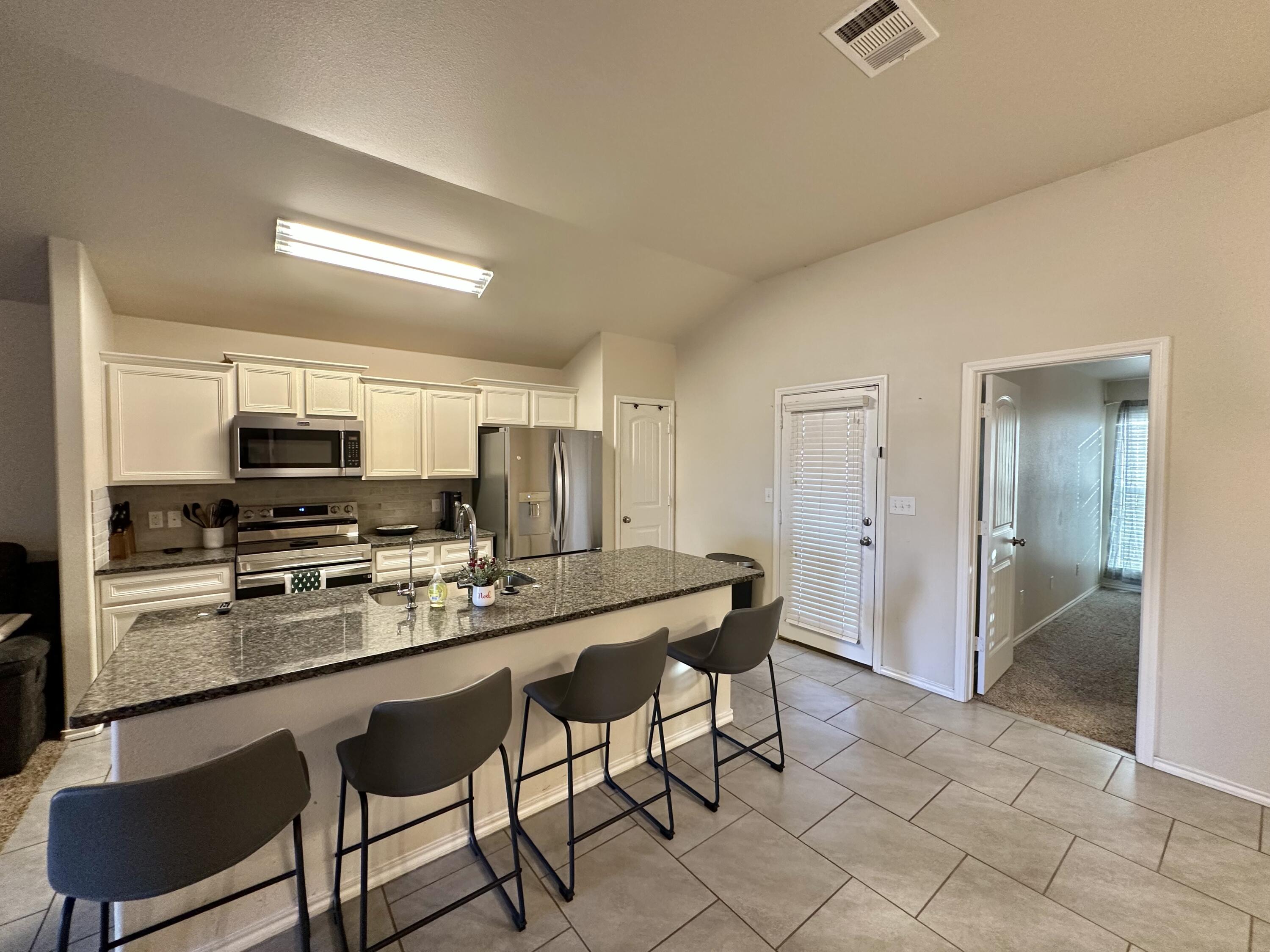 10411 Valencia Avenue Lubbock, TX 79424 - Photo 4 of 16 a kitchen with a dining table chairs and refrigerator