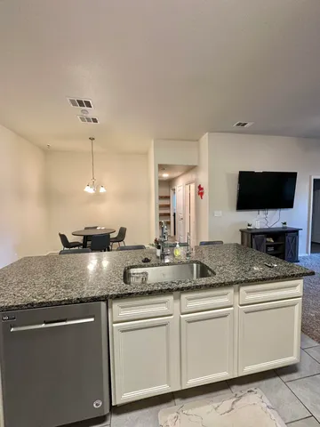 a kitchen with granite countertop a sink and white cabinets