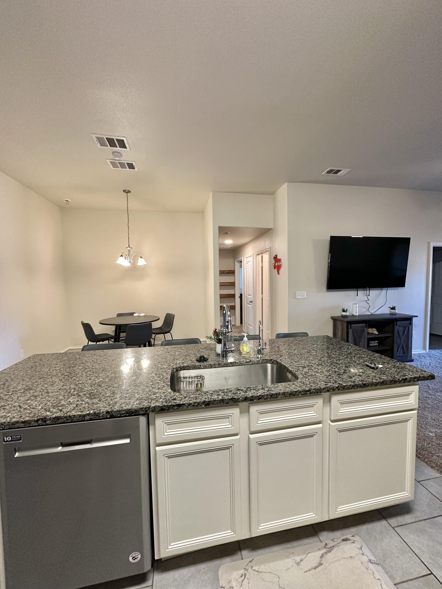 10411 Valencia Avenue Lubbock, TX 79424 - Photo 6 of 16 a kitchen with granite countertop a sink and white cabinets