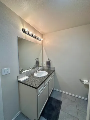 a bathroom with a granite countertop sink and a mirror