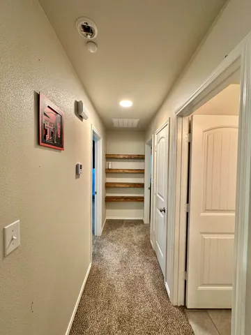 a view of a hallway with wooden shelves