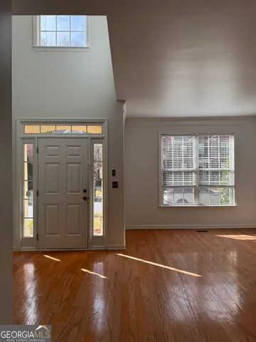 an empty room with wooden floor and windows