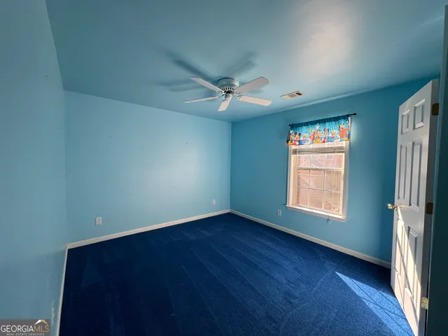 an empty room with a window and a ceiling fan
