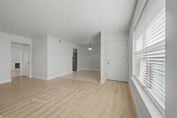 a view of an empty room with wooden floor and a window