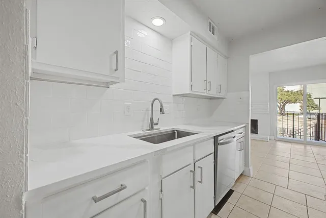 a kitchen with white cabinets a sink and dishwasher