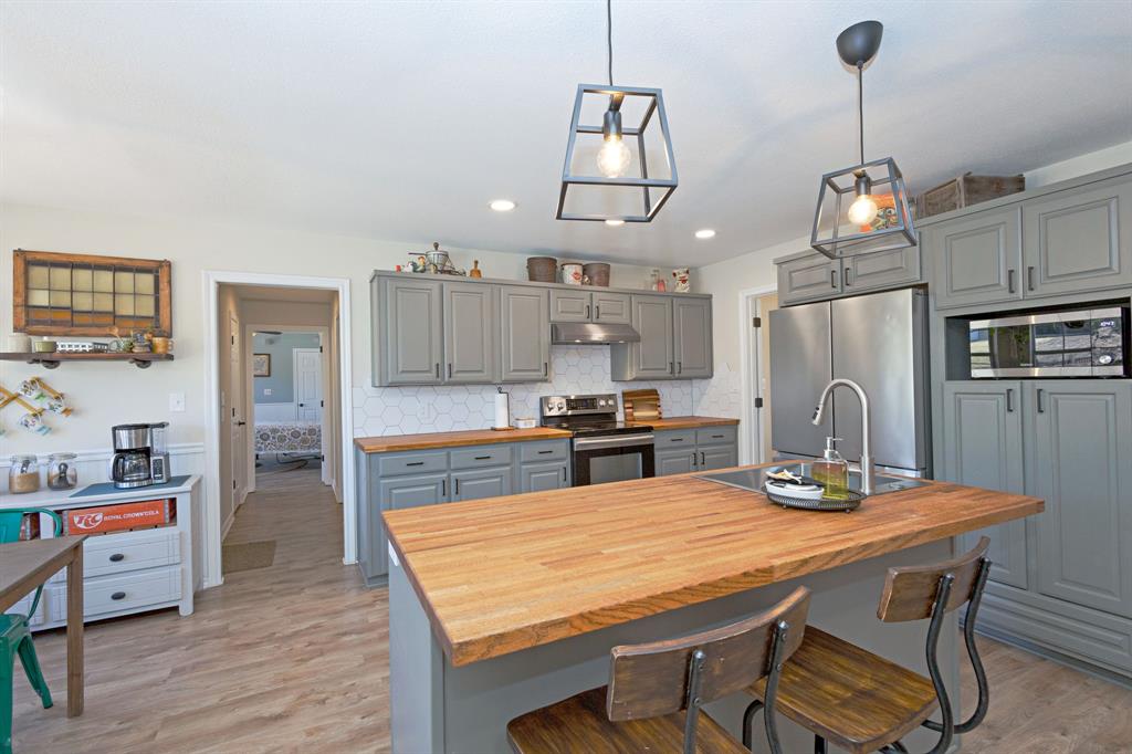 13508 Deussen Road Ponder, TX 76259 - Photo 13 of 40 a kitchen with stainless steel appliances granite countertop a kitchen island a stove a table and chairs