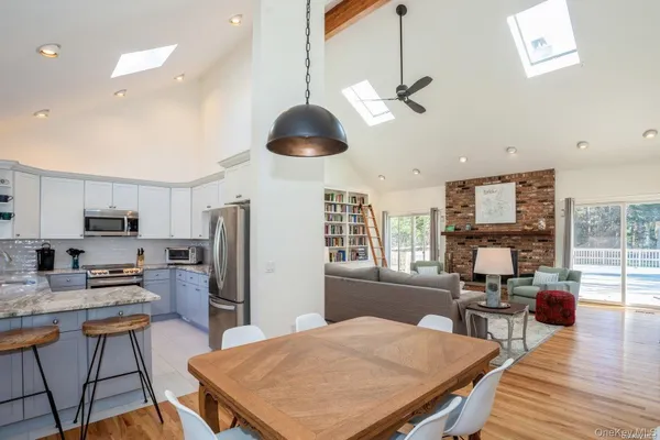 a kitchen with stainless steel appliances granite countertop a stove top oven a refrigerator a sink dishwasher a dining table and chairs with wooden floor