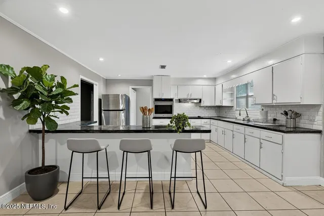 a kitchen with stainless steel appliances kitchen island granite countertop a sink a stove a microwave and cabinets