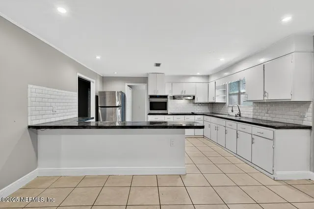 a large kitchen with granite countertop a white stove top oven and cabinets