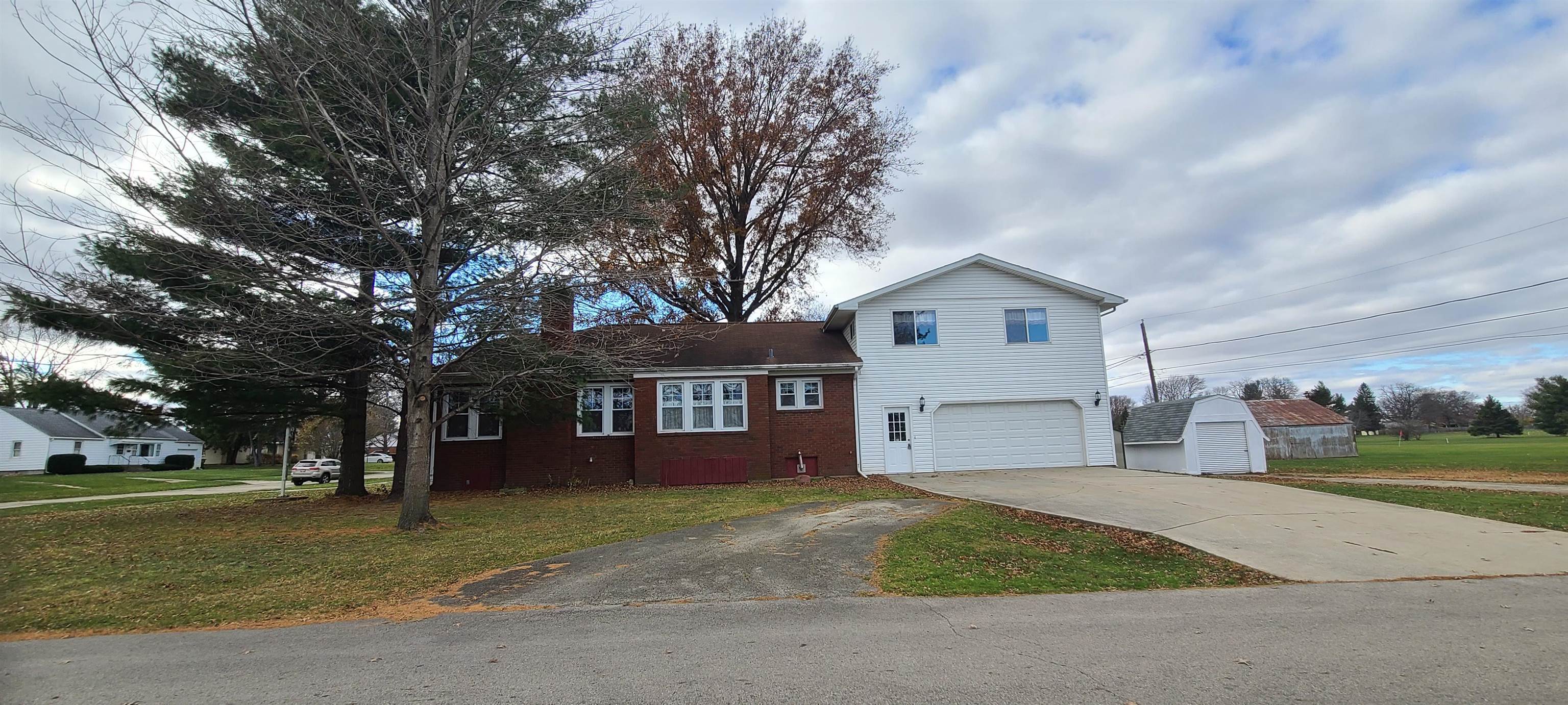 a front view of a house with a garden and trees