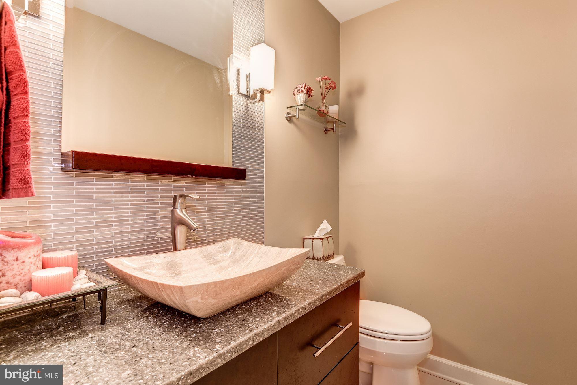 9204 Fall River Lane Potomac, MD 20854 - Photo 14 of 30 a bathroom with a granite countertop toilet a sink and a mirror