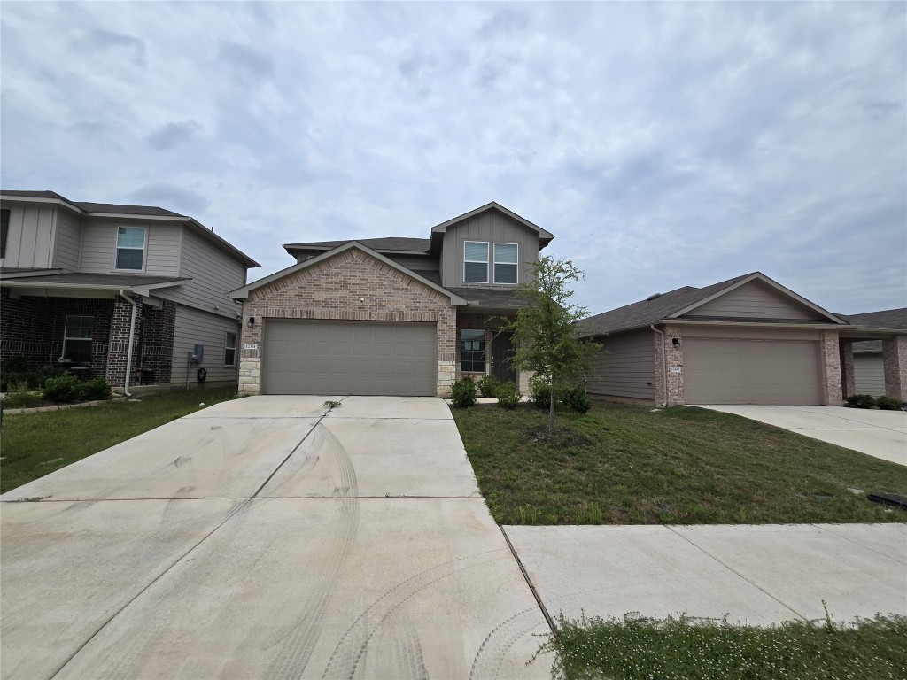 View of front of house featuring concrete driveway, a garage, a front lawn, and brick siding