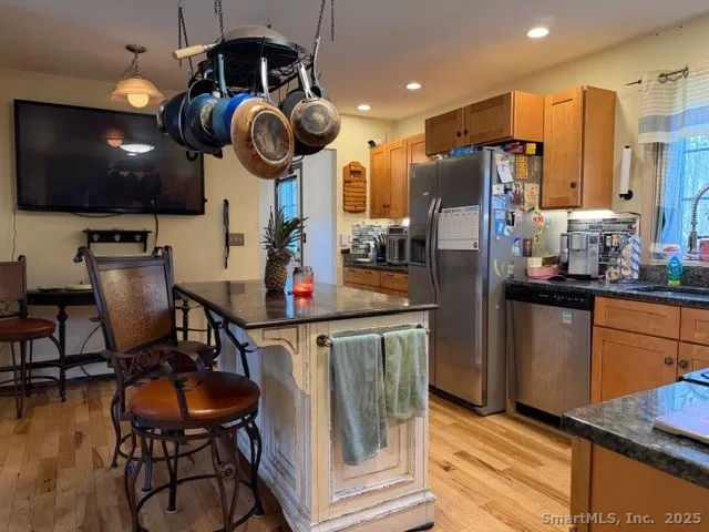 a kitchen with stainless steel appliances granite countertop a stove a refrigerator a dining table and chairs with wooden floor