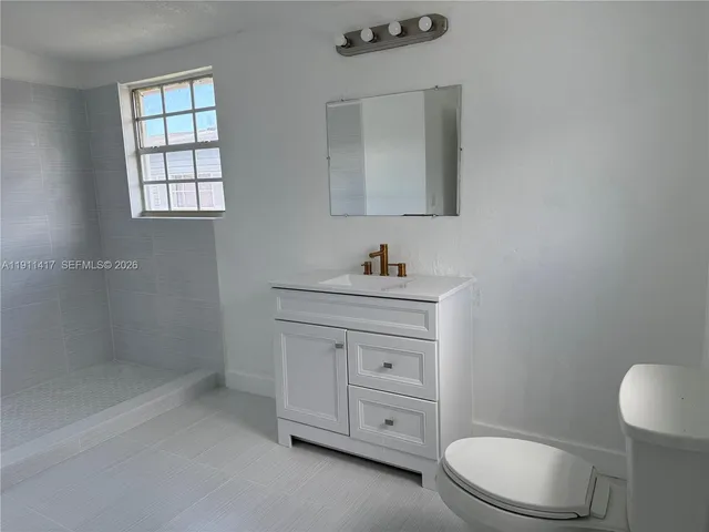 a bathroom with a toilet sink vanity and mirror