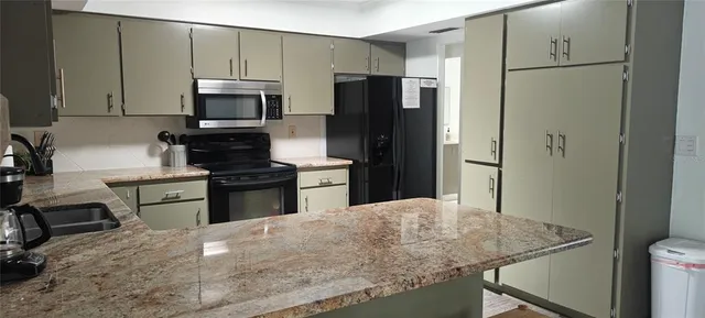 a kitchen with stainless steel appliances granite countertop a stove top oven a sink a dining table and chairs with wooden floor