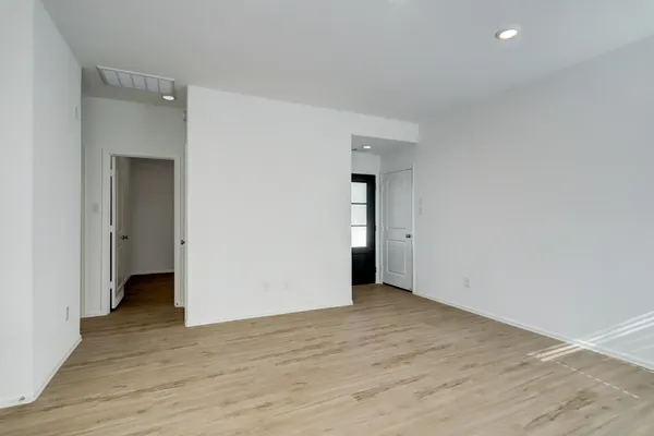 a view of an empty room with wooden floor and closet