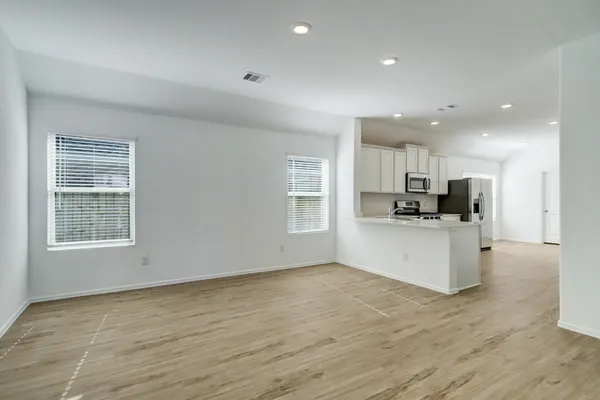 a view of kitchen with stainless steel appliances kitchen island granite countertop a stove a sink a refrigerator and white cabinets with wooden floor