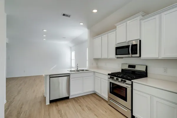 a kitchen with stainless steel appliances a white stove top oven cabinets and a wooden floor