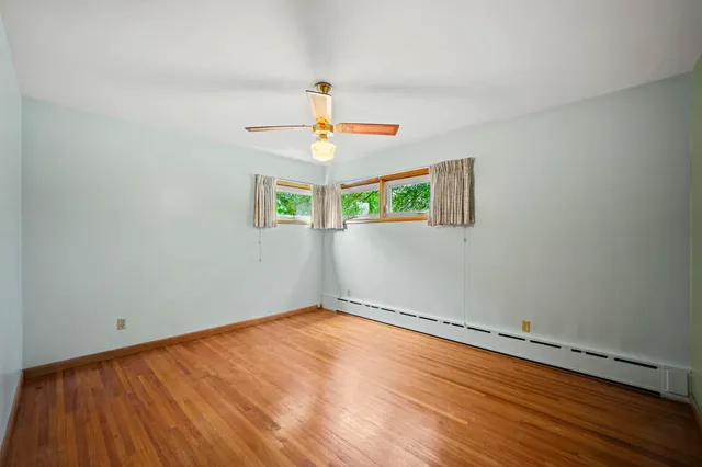 an empty room with windows and fan
