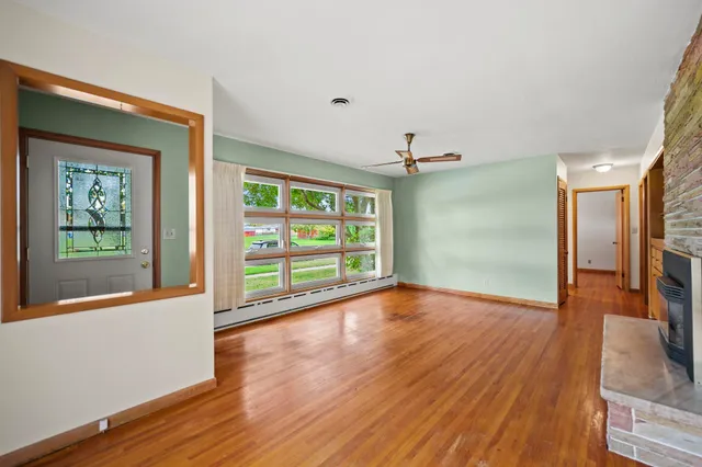 a view of an empty room with a window and wooden floor