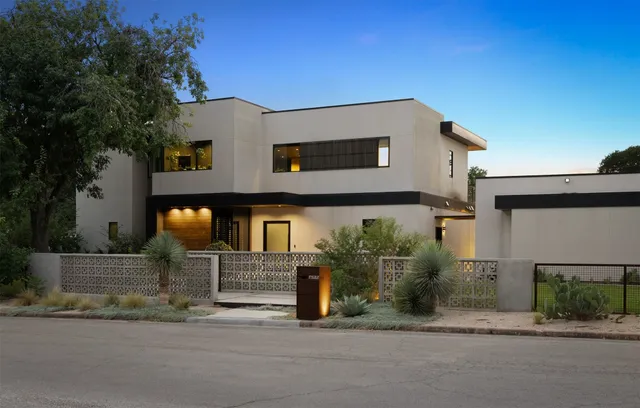 a front view of a house with garage and plants
