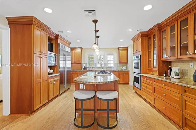 a large kitchen with stainless steel appliances kitchen island granite countertop a refrigerator a stove and a wooden cabinets