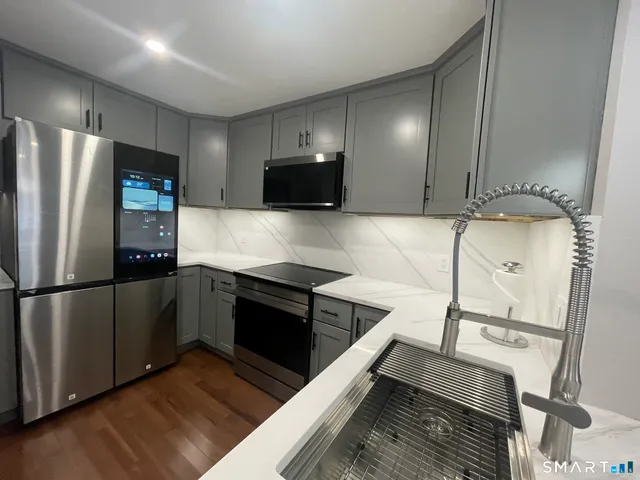 a kitchen with stainless steel appliances granite countertop a refrigerator a stove and a sink