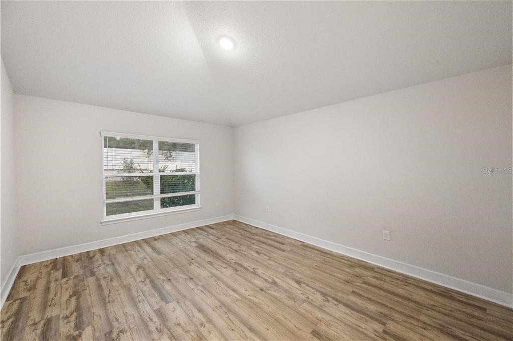 14429 Potterton Circle Hudson, FL 34667 - Photo 22 of 36 an empty room with wooden floor and windows