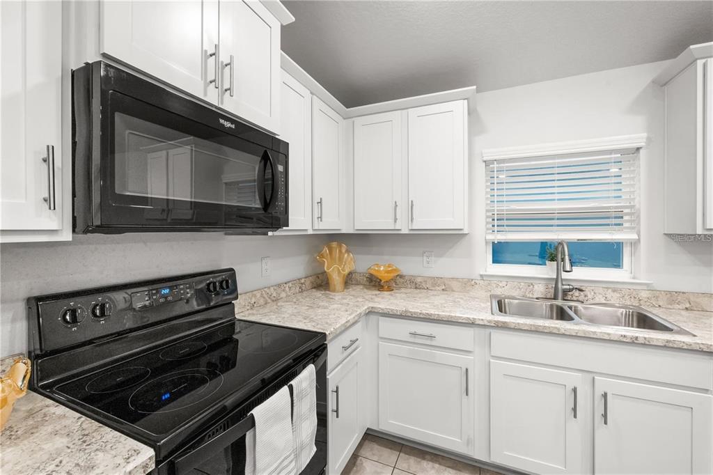 14429 Potterton Circle Hudson, FL 34667 - Photo 7 of 36 a kitchen with granite countertop a stove microwave and sink