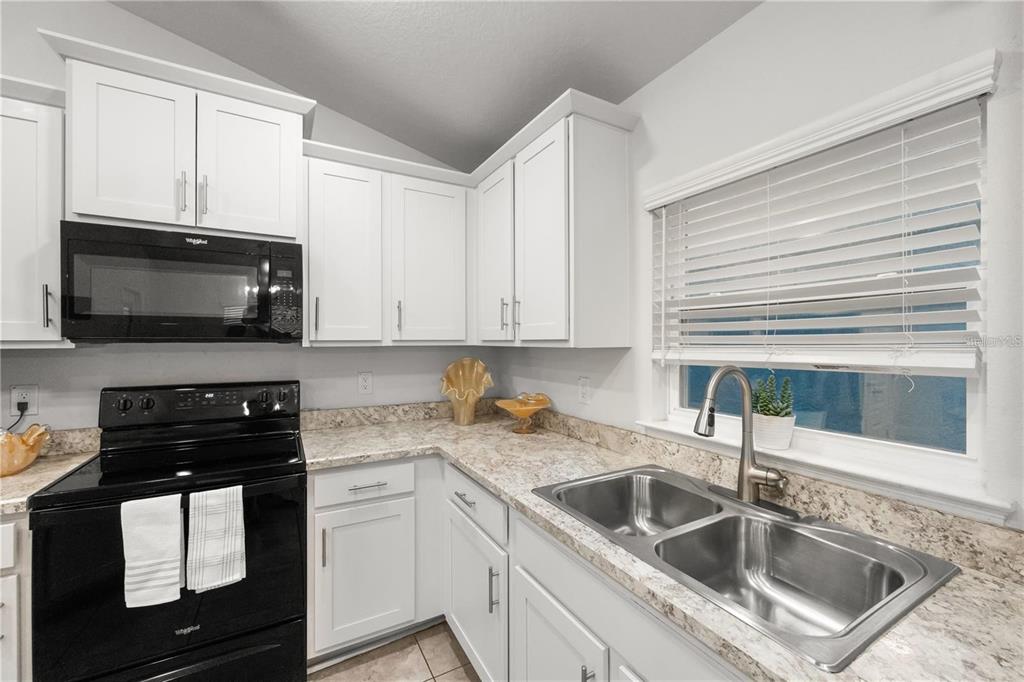 14429 Potterton Circle Hudson, FL 34667 - Photo 8 of 36 a kitchen with white cabinets a sink and a stove with wooden floor