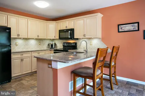 a kitchen with stainless steel appliances granite countertop a stove top oven a sink a dining table and chairs with wooden floor